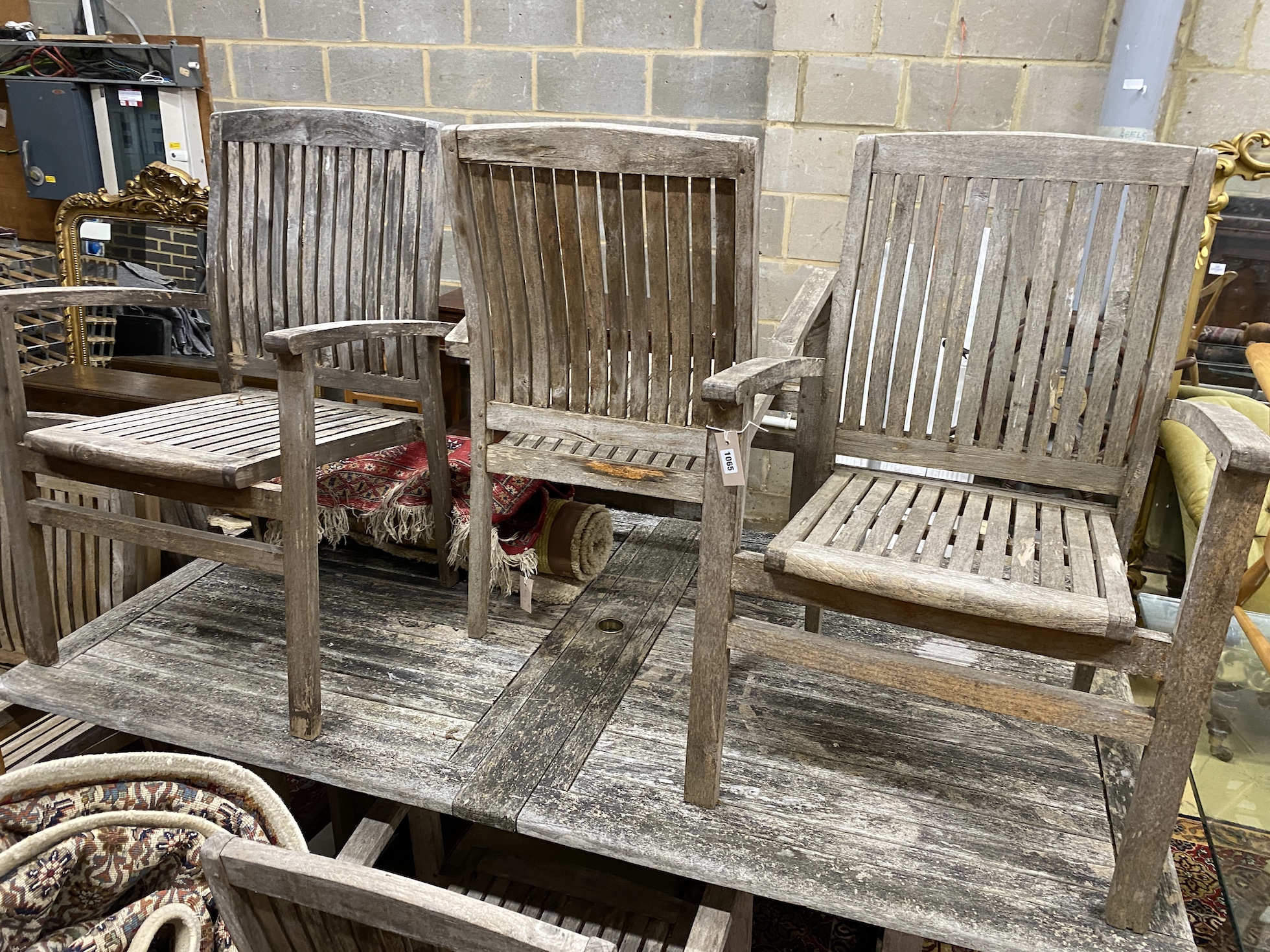 A rectangular weathered teak extending garden table, minimum length 190cm, depth 109cm, height 74cm and eight elbow chairs
